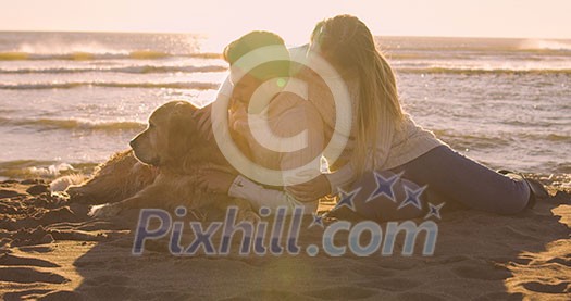 Couple With A Dog enjoying time  together On The Beach at autumn day