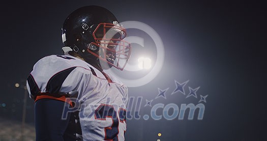 portrait of young confident American football player  standing on field at night