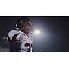 portrait of young confident American football player  standing on field at night