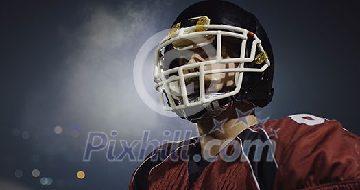 portrait of young confident American football player  standing on field at night