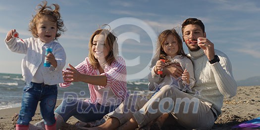 Family with kids resting and having fun at beach during autumn day