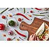 A woman makes a burrito with fresh vegetables on a wooden board. A step-by-step recipe for cooking. Top view, flat lay.