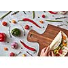 A woman makes a burrito with fresh vegetables on a wooden board. A step-by-step recipe for cooking. Top view, flat lay.