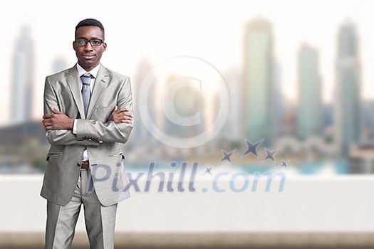 Portrait of young black businessman standing on balcony in front of the big city