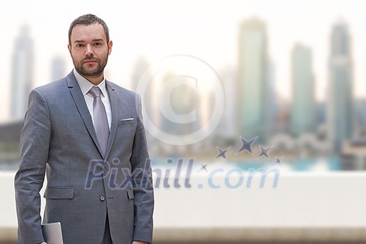 Portrait of young businessman standing on balcony in front of the big city Portrait of young businessman standing on balcony in front of the big city