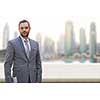 Portrait of young businessman standing on balcony in front of the big city