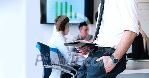 Businessman using tablet computer in office with coworkers in background Businessman using tablet computer in office with coworkers in background
