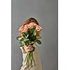 A bouquet of beige roses in a girl's hand on a gray background. Mothers Day.