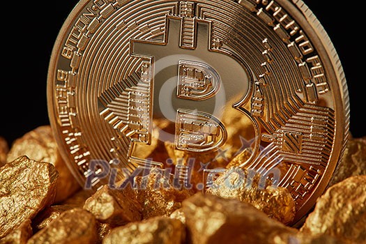 Closeup of gold nugget and Gold Bitcoin Coin on black background . Bitcoin as desirable as digital gold concept. Bitcoin cryptocurrency.