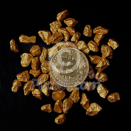 Bitcoin laying on stacked gold nuggets rendered on black background flat lay. Bitcoin as desirable as digital gold concept. Bitcoin cryptocurrency.