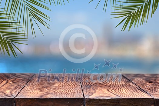 wooden table or wooden mock up with palm trees against the background of a blurry city . Natural background with copy space. Can be used for display products.