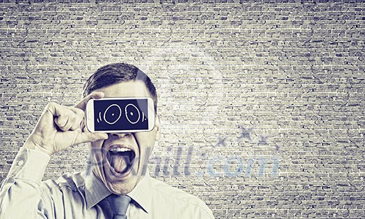Young handsome businessman hiding mouth behind mobile phone Young handsome businessman hiding mouth behind mobile phone