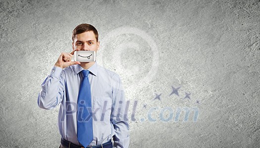 Young handsome businessman hiding mouth behind mobile phone
