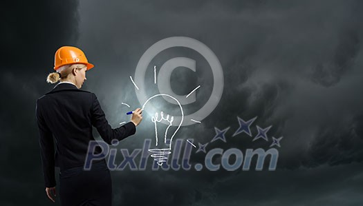 Rear view of woman in hardhat drawing light bulb Rear view of woman in hardhat drawing light bulb
