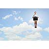 Young pretty businesswoman sitting on cloud high above city