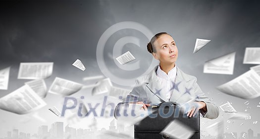 Young pretty businesswoman sitting with briefcase in hands