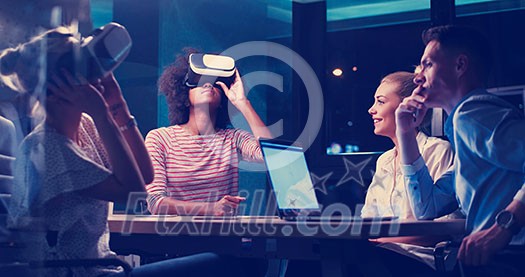 Multiethnic Business team using virtual reality headset in night office meeting  Developers meeting with virtual reality simulator around table in creative office.