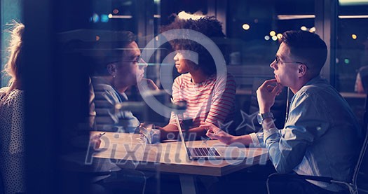 Multiethnic startup business team on meeting in modern night office interior brainstorming, working on laptop Multiethnic startup business team on meeting in modern night office interior brainstorming, working on laptop