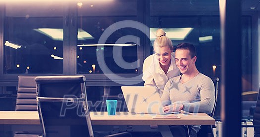 Two young designers are working on a new project in the night office using modern technology Two young designers are working on a new project in the night office using modern technology