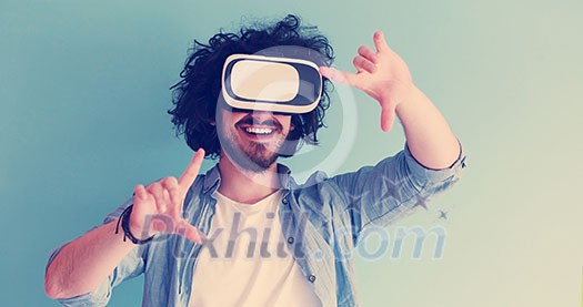 Happy man getting experience using VR headset glasses of virtual reality, isolated on blue background