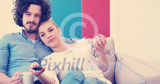 Young couple on the sofa watching television together in their luxury home Young couple on the sofa watching television together in their luxury home