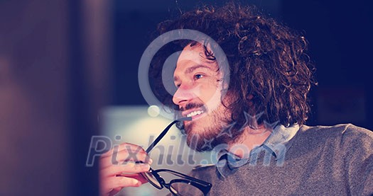 Young man working on computer at night in dark office. The designer works in the later time. Young man working on computer at night in dark office. The designer works in the later time.