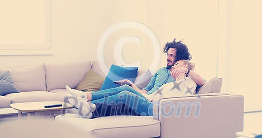 Young couple on the sofa watching television together in their luxury home Young couple on the sofa watching television together in their luxury home