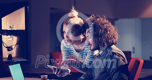 Two young designers are working on a new project in the night office using modern technology Two young designers are working on a new project in the night office using modern technology