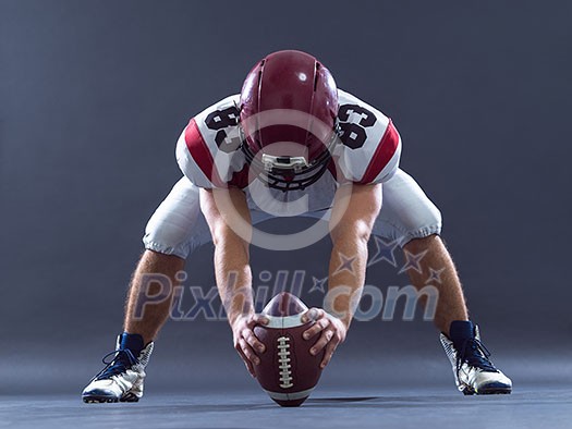 American football player getting ready before starting the game while standing against gray background