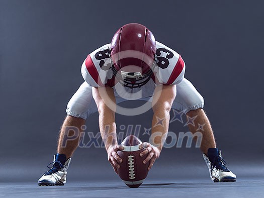 American football player getting ready before starting the game while standing against gray background American football player getting ready before starting the game while standing against gray background