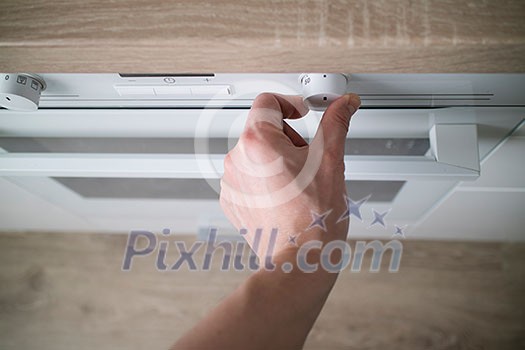 Close up of man hand turning on the white oven in modern kitchen. Modern oven with temperature setting