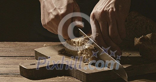 Pieces of white bread on a wooden board, the baker cuts a piece of bread with a crispy crust, a piece falls on a cutting board crumbs of bread fall on the table. Slow motion. 1080p Full HD video Pieces of white bread on a wooden board, the baker cuts a piece of bread with a crispy crust, a piece falls on a cutting board crumbs of bread fall on the table. Slow motion. 1080p Full HD video