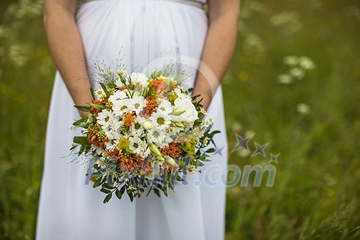 Beautiful bride with bouquet. Fashion brunette model outdoors. Portrait beauty model in white bridal dress holding flowers