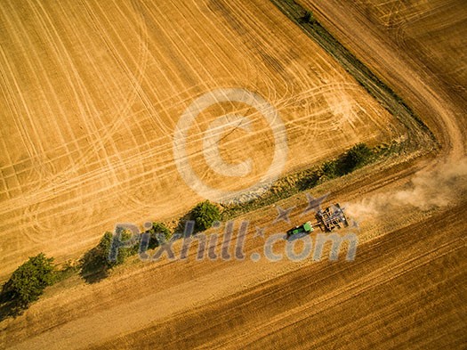 Aerial view of a tractor working a field after harvest