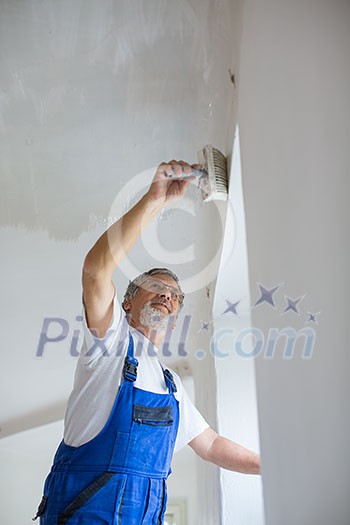 Senior painter man at work with a paint bucket, wall painting concept Senior painter man at work with a paint bucket, wall painting concept