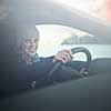 Woman driving a car - female driver at a wheel of a modern car, looking happy, smiling with a relaxed smile (shallow DOF; color toned image)