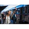 Pretty young woman boarding a train/having arrived to her destination, waiting for her friends to pick her up (color toned image)