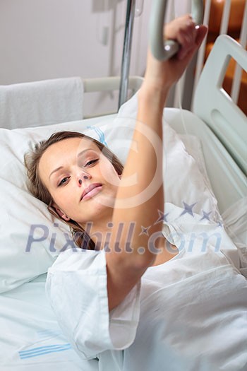 Pretty, young, female patient in a modern hospital room. Getting better fast after a surgery - pensive yet positive, thinking ahead, making plans (shallow DOF; color toned image) Pretty, young, female patient in a modern hospital room. Getting better fast after a surgery - pensive yet positive, thinking ahead, making plans (shallow DOF; color toned image)