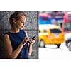 Pretty, young businesswoman talking on the phone in front of a modern building in Manhattan (shallow DOF; color toned image)