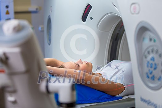 Pretty, young woman goiing through a Computerized Axial Tomography (CAT) Scan medical test/examination in a modern hospital (color toned image; shallow DOF) Pretty, young woman goiing through a Computerized Axial Tomography (CAT) Scan medical test/examination in a modern hospital (color toned image; shallow DOF)