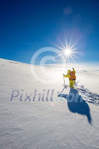 High altitude mountain explorer walking through deep snow in high mountains on a freezing winter day