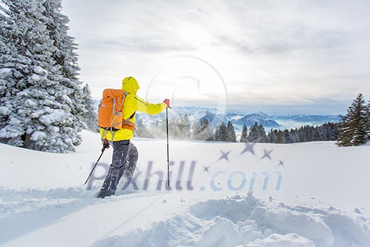 Young man snowshoeing in high mountains, enjoying splendid winter weather with abundance of snow