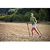 Pretty, young woman nordic walking on a forest path, taking in the fresh air, getting the daily dose of exercise