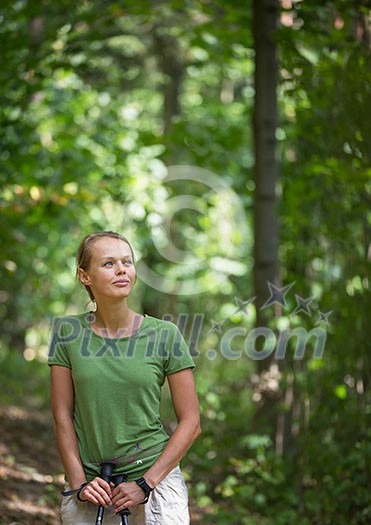 Pretty, young woman nordic walking on a forest path, taking in the fresh air, getting the daily dose of exercise Pretty, young woman nordic walking on a forest path, taking in the fresh air, getting the daily dose of exercise