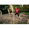 Young woman running outdoors in a forest, going fast (motion blurred image)