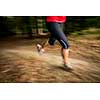 Young woman running outdoors in a forest, going fast (motion blurred image)