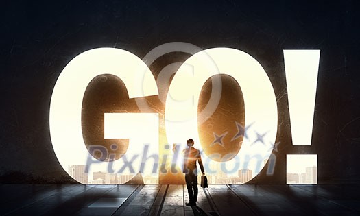 Back view of businessman standing in light of GO word Back view of businessman standing in light of GO word