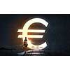 Silhouette of businesswoman in light of big euro symbol