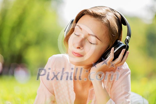 Young pretty lady in park listening to music