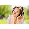 Young pretty lady in park listening to music